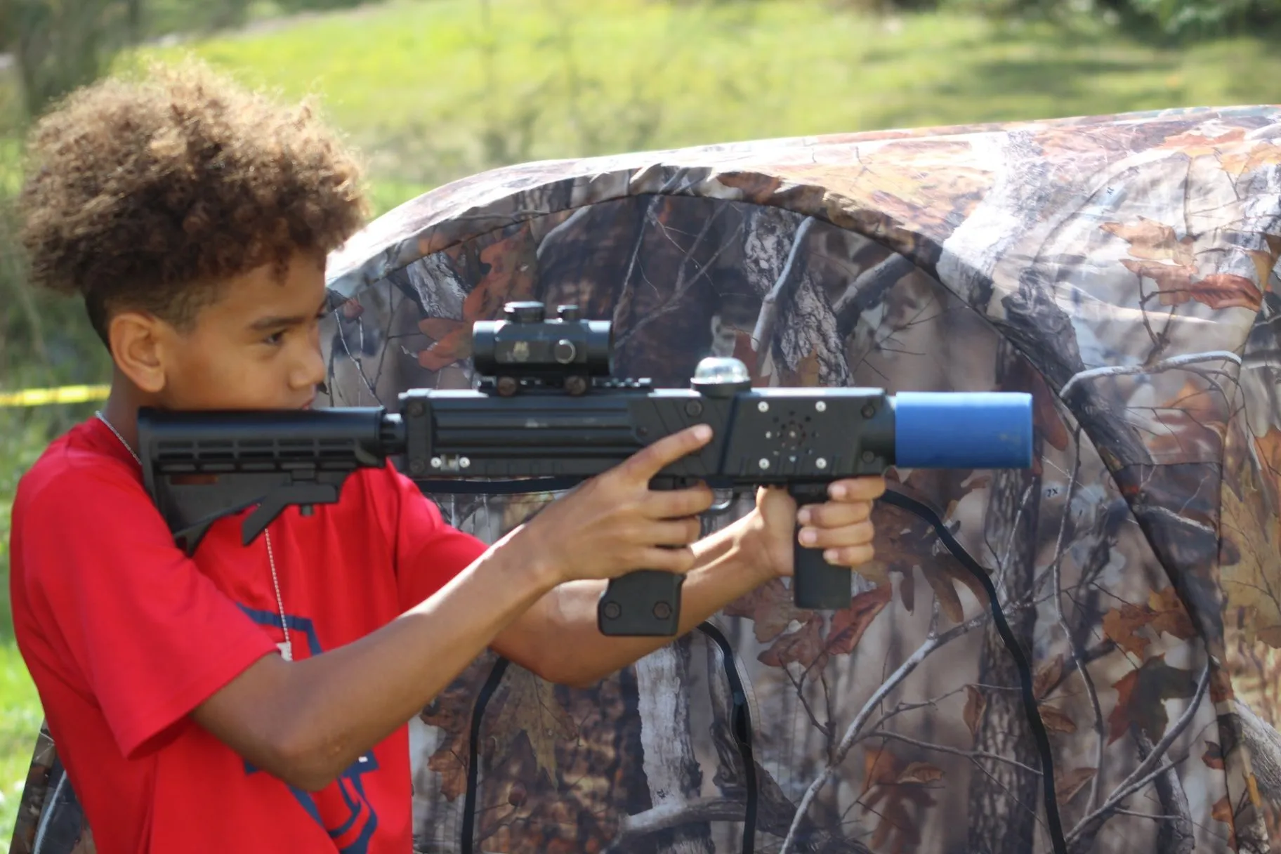 Player aiming a tagger beside a camouflaged blind